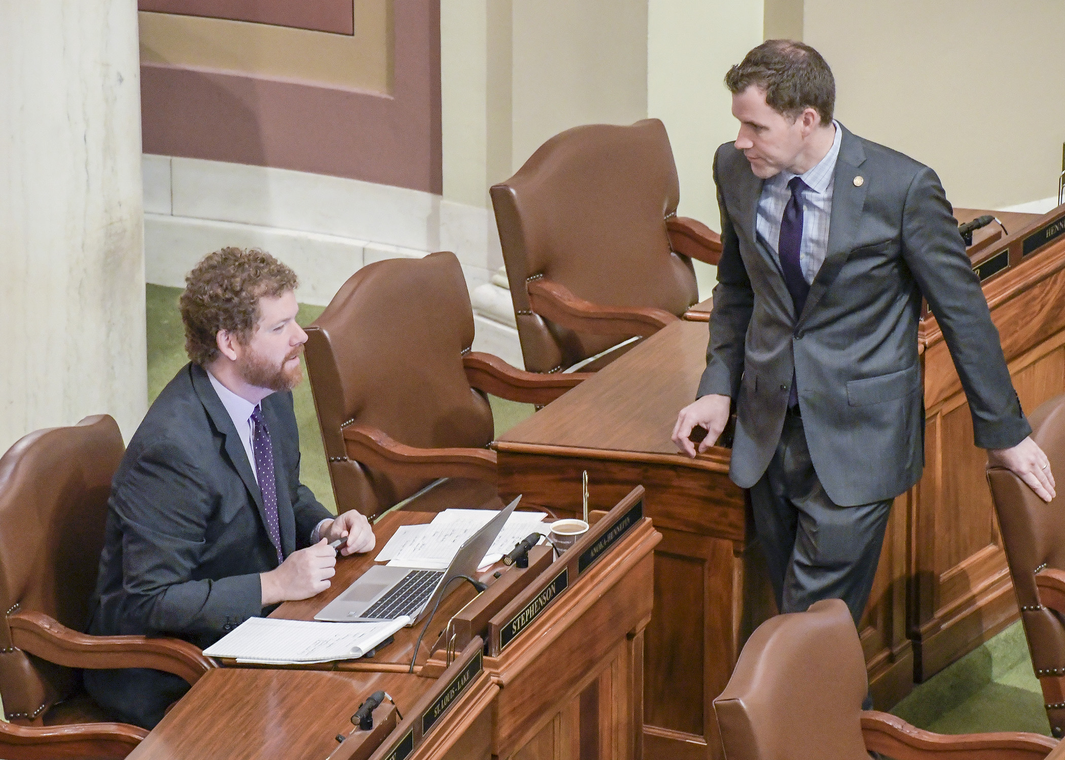 Rep. Zack Stephenson (left), chair of the House Commerce Finance and Policy Committee, and Rep. Jamie Long, chair of the House Climate and Energy Finance and Policy Committee, confer on the House floor prior to Monday. Photo by Andrew VonBank
